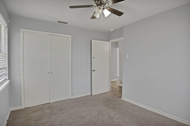 unfurnished bedroom featuring baseboards, visible vents, a closet, a textured ceiling, and carpet flooring