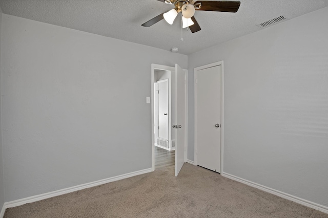 empty room with a ceiling fan, baseboards, visible vents, a textured ceiling, and light colored carpet