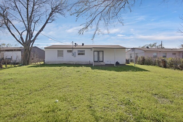 rear view of house with a lawn and a fenced backyard