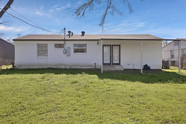 rear view of property with brick siding, a yard, and fence