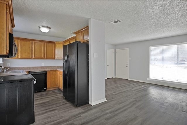 kitchen with baseboards, visible vents, dark wood-style flooring, black appliances, and light countertops