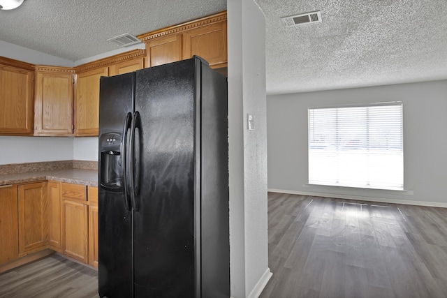 kitchen featuring baseboards, wood finished floors, visible vents, and black refrigerator with ice dispenser