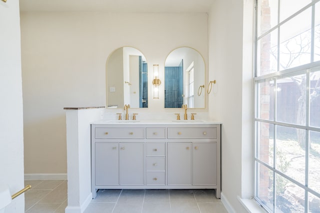 bathroom with tile patterned flooring, double vanity, baseboards, and a sink