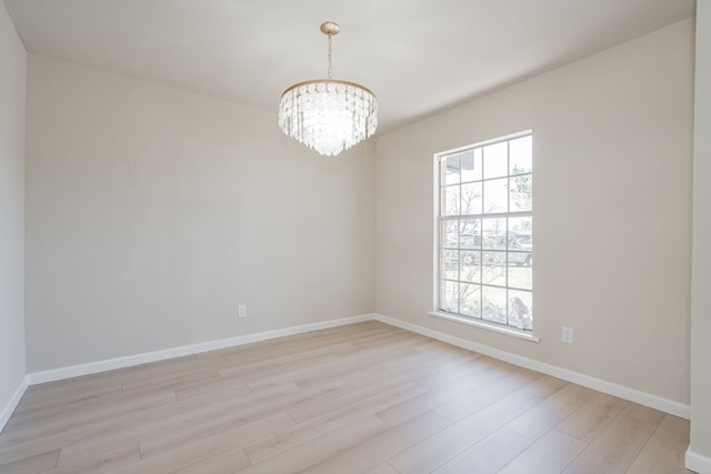 unfurnished room featuring a notable chandelier, light wood-style floors, and baseboards