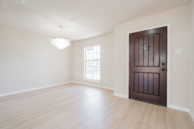 entrance foyer featuring a notable chandelier, light wood-style flooring, and baseboards