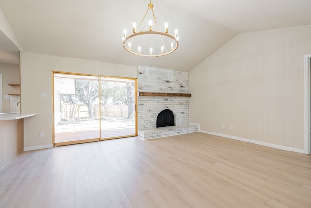 unfurnished living room featuring a notable chandelier, wood finished floors, a fireplace, baseboards, and vaulted ceiling