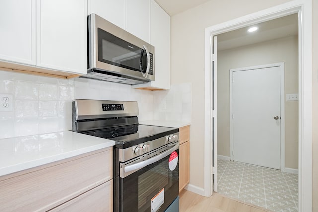 kitchen with backsplash, white cabinets, stainless steel appliances, and light countertops