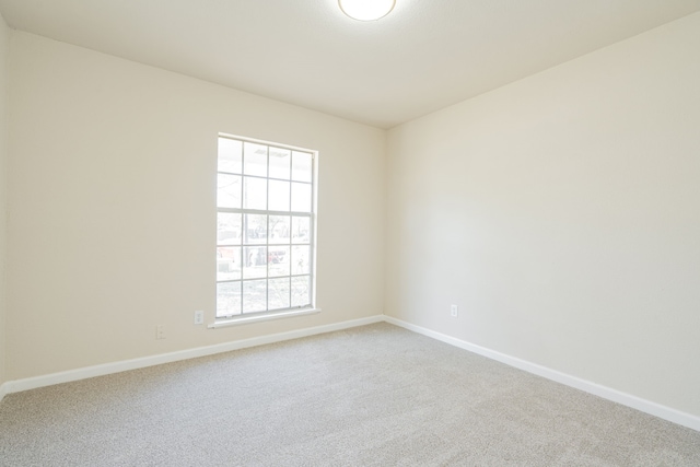 carpeted spare room featuring baseboards