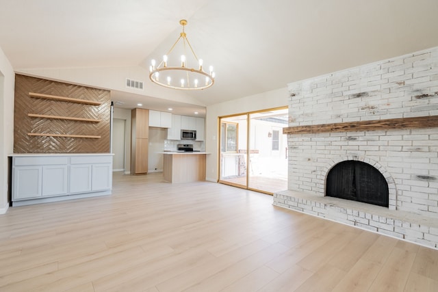 unfurnished living room with visible vents, a chandelier, vaulted ceiling, a fireplace, and light wood-style floors