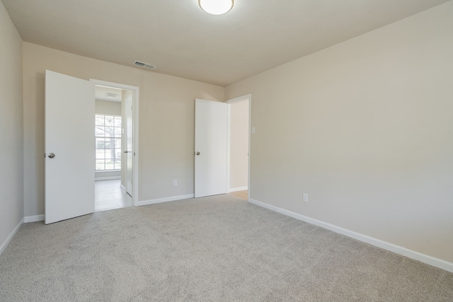 empty room with visible vents, baseboards, and light colored carpet