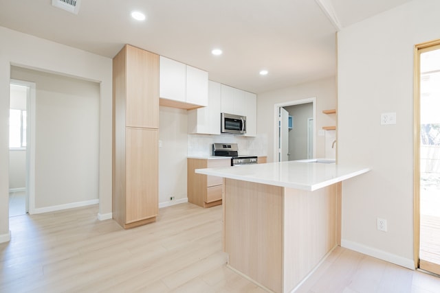 kitchen featuring visible vents, recessed lighting, a peninsula, white cabinets, and stainless steel appliances