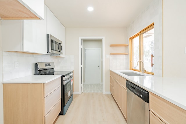 kitchen with light brown cabinets, decorative backsplash, appliances with stainless steel finishes, and a sink