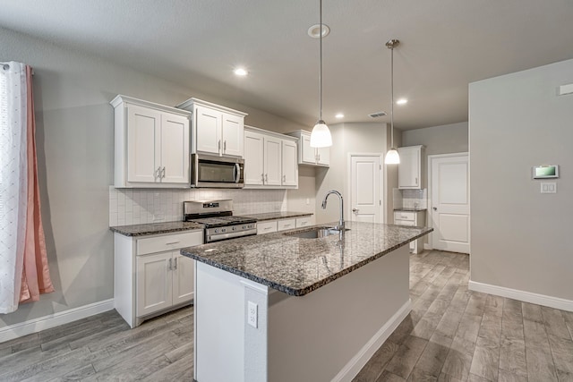 kitchen featuring tasteful backsplash, light wood-style floors, stainless steel appliances, and a sink