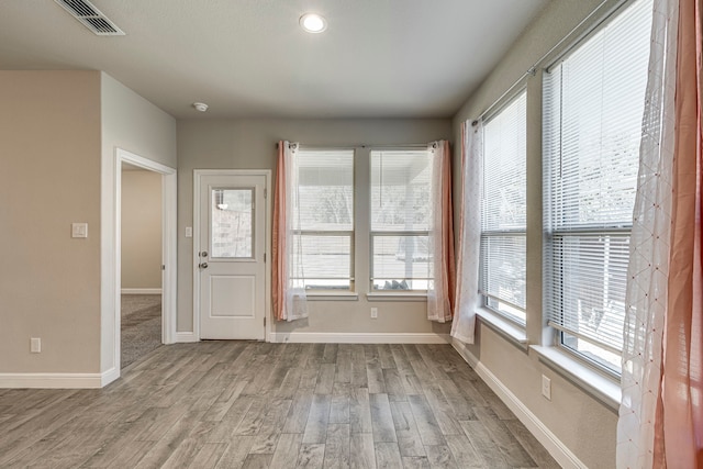 empty room featuring baseboards, visible vents, and light wood finished floors