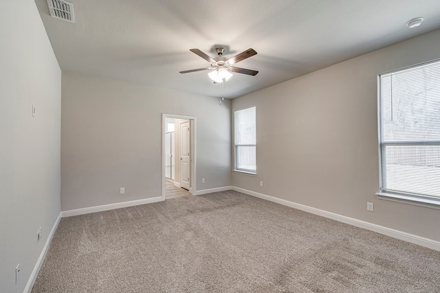 spare room with visible vents, light carpet, baseboards, and a ceiling fan