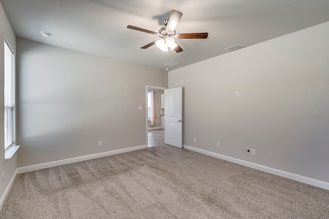 carpeted empty room with baseboards, visible vents, and ceiling fan