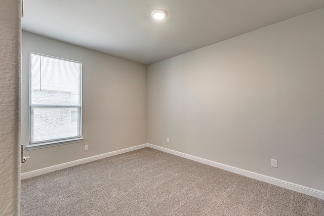 carpeted empty room featuring baseboards