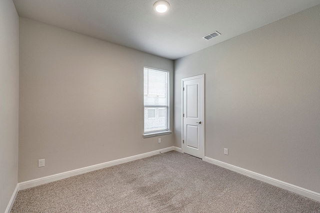 empty room featuring light colored carpet, visible vents, and baseboards