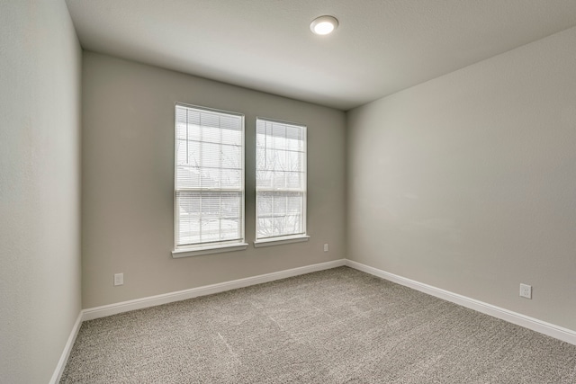 carpeted spare room featuring baseboards