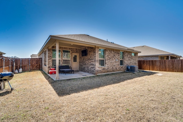 back of property with a patio, central AC unit, a fenced backyard, a lawn, and brick siding