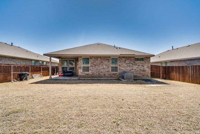 rear view of property with a patio, central air condition unit, a fenced backyard, and brick siding