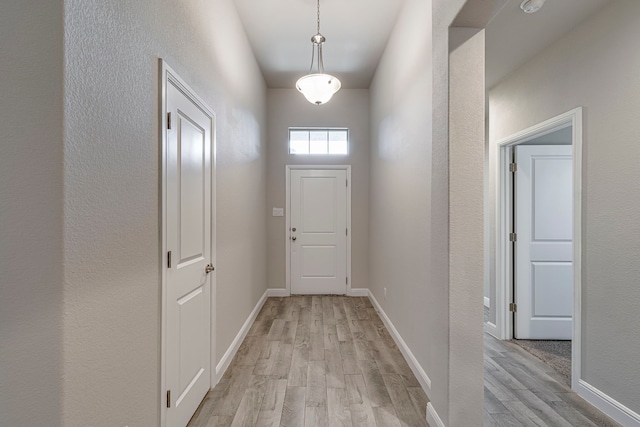 doorway with baseboards and light wood-style floors