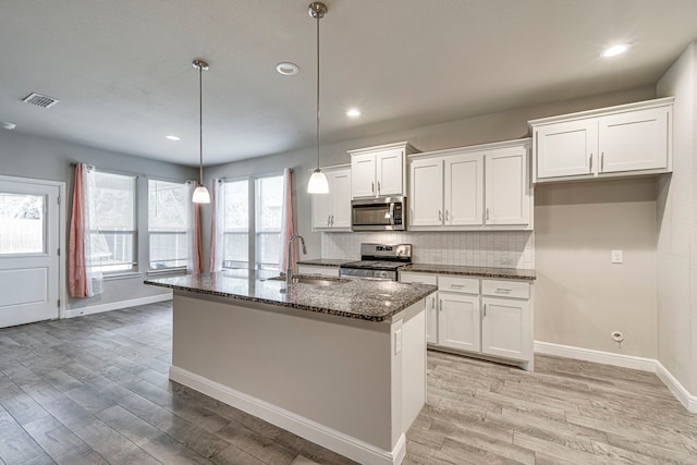 kitchen featuring a sink, stainless steel appliances, light wood finished floors, and white cabinetry