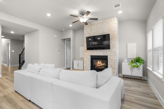 living area with visible vents, light wood-style flooring, stairway, a fireplace, and baseboards