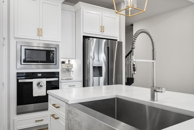 kitchen with decorative light fixtures, white cabinets, appliances with stainless steel finishes, and light stone countertops