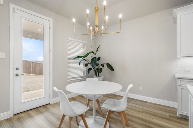 dining space featuring baseboards, an inviting chandelier, and light wood finished floors