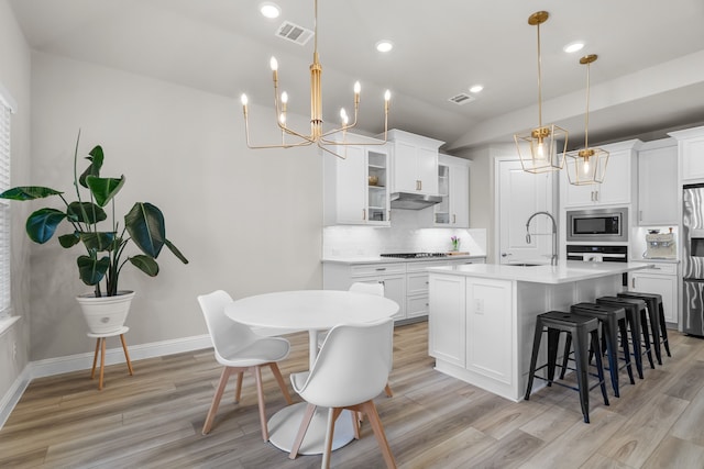 kitchen featuring a breakfast bar area, visible vents, a sink, stainless steel appliances, and tasteful backsplash