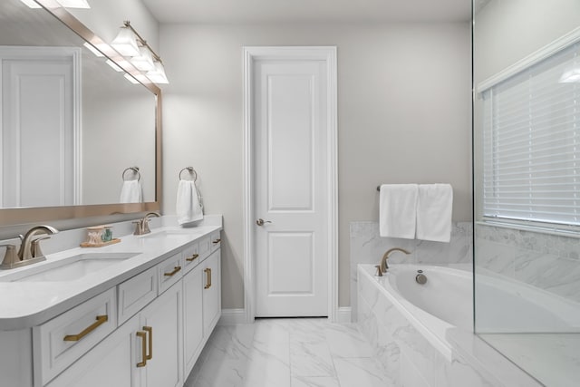 full bathroom with a bath, marble finish floor, double vanity, and a sink