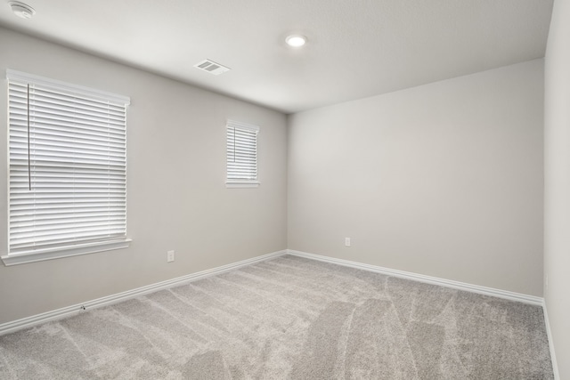 carpeted empty room featuring visible vents and baseboards