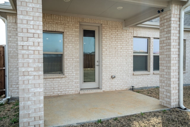 property entrance featuring brick siding and a patio