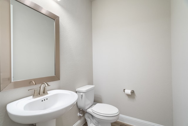 bathroom featuring a sink, baseboards, and toilet