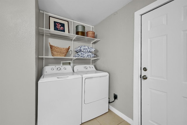 laundry area with light tile patterned flooring, laundry area, washer and dryer, and baseboards