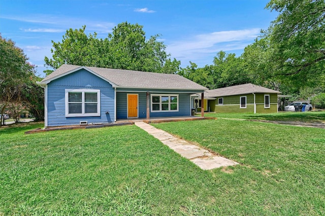 ranch-style home featuring a shingled roof and a front lawn