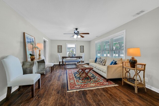 living room featuring visible vents, a ceiling fan, baseboards, and wood-type flooring