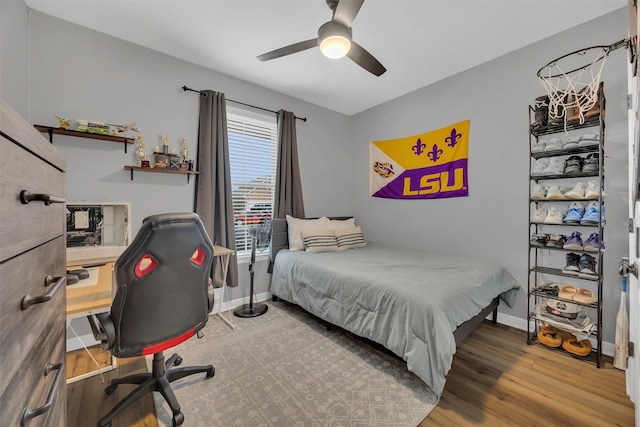 bedroom with a ceiling fan, wood finished floors, and baseboards