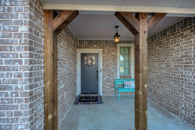 doorway to property with brick siding and a porch