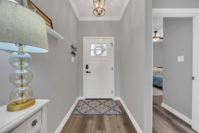 foyer featuring a chandelier, baseboards, wood finished floors, and crown molding