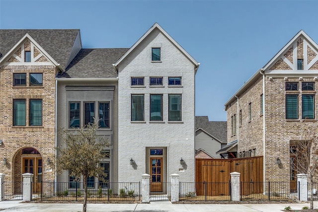 multi unit property with brick siding and a fenced front yard