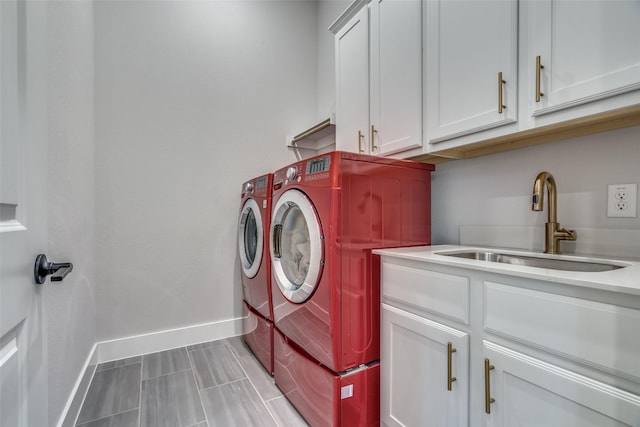 laundry area featuring a sink, cabinet space, baseboards, and washing machine and clothes dryer