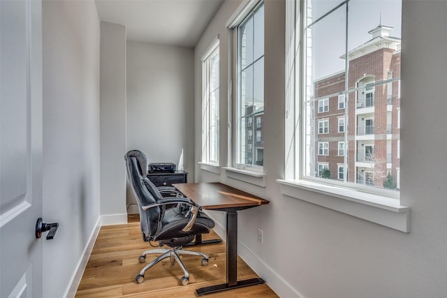 office space with a wealth of natural light, baseboards, and wood finished floors