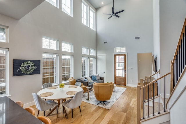 dining room featuring stairway, a ceiling fan, visible vents, wood finished floors, and baseboards