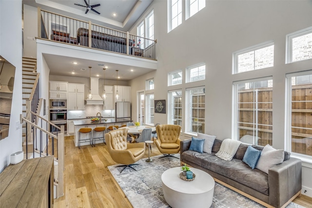 living room featuring ceiling fan, stairway, and light wood-style flooring