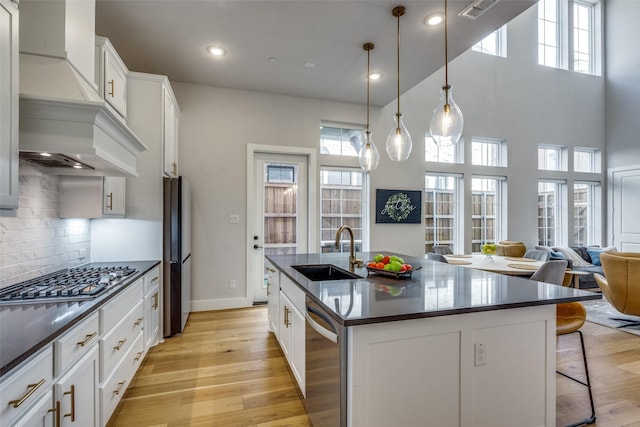 kitchen featuring dark countertops, light wood finished floors, appliances with stainless steel finishes, and a sink