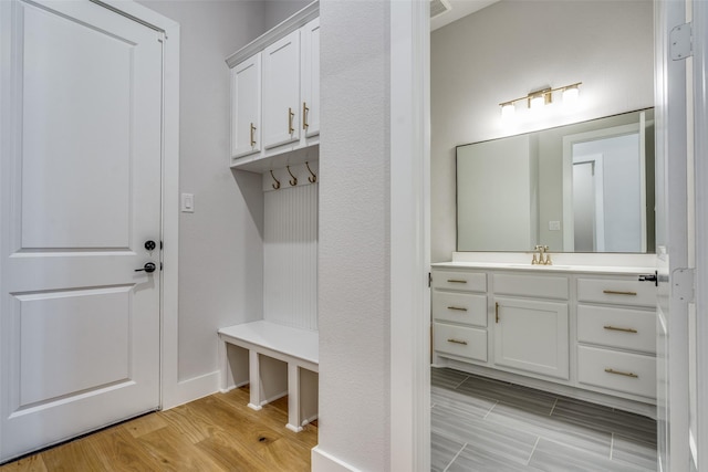 mudroom featuring light wood-style floors, visible vents, and a sink