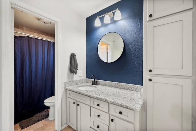 bathroom with vanity, curtained shower, tile patterned floors, toilet, and a textured wall