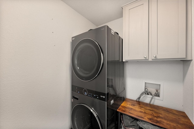 washroom with cabinet space and stacked washer and clothes dryer